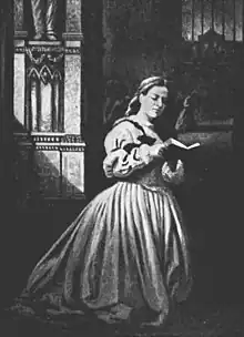 Noir et blanc. Une jeune femme à genoux lit un livre.