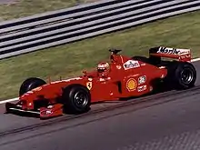 Monoplace rouge, vue de trois-quarts, dans son ensemble, sur une piste sèche.