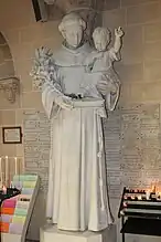 Statue de St Antoine de Padoue avec ses attributs : l’enfant Jésus, la bure franciscaine, le livre et le lys.