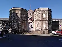 Photographie en couleurs d'une porte encadrée par deux tours massives.