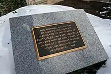 Photo agrandie d'une plaque comportant des inscriptions or sur fond noir avec un large cadre gris en pierre.