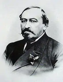 photographie noir et blanc : portrait d'homme un peu dégarni, avec moustache et barbiche