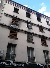 Vue du premier au 4e&nbsp;étage d'un immeuble, certaines fenêtres ont des traces noires de suie sur le dessus, d'autres ont des tasseaux ou sont murées.