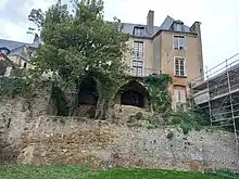 Vestiges d'une muraille et d'un échafaudage, et deux embrasures ouvertes en ogive, surmontés d'un bâtiment