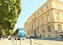 La faculté de droit, un bâtiment ancien. Un tramway passe devant, à côté de quelques arbres.