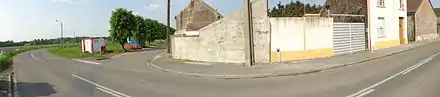Panorama réalisé à Fresnes-sur-Escaut montrant la rue et les habitations. Une petite borne en béton apparaît le long d'un mur, il s'agit d'une tête de puits non matérialisée indiquant que le puits Jeanne Colard no&nbsp;1, creusé en 1718 et abandonné en 1721, se situe quelques mètres derrière.