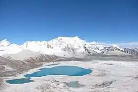 Vue du versant ouest du Gangkhar Puensum depuis le Gophu La, avec à gauche du sommet la longue arête horizontale qui mène à son sommet secondaire, le Liankang Kangri (7&nbsp;535&nbsp;m).