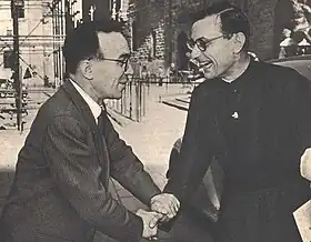 Photo en noir et blanc de Giorgio La Pira, souriant et de profil, serrant chaleureusement la main d'un prêtre