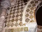 Photographie des carreaux de céramique lustrée, monochromes et polychromes, qui ornent le mihrab et son mur. Leurs décors variés comportent divers ornements géométriques, floraux et végétaux.