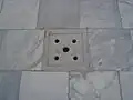 Détail du pavement en marbre blanc. Les trous dans le sol permettent l'évacuation des eaux dans les citernes.