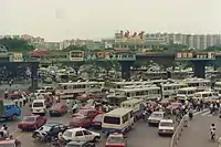 La place à l'est de la gare de Canton en 1991. On peut remarquer la prédominance des caractères chinois traditionnels dans les logos des marques de cette époque, notamment Jianlibao&nbsp;(en) (健力寶), Rejoice (飄柔) et 萬家樂 ; seule Head & Shoulders (海飞丝) est imprimé en caractères simplifiées. En Chine continentale, il était autorisé de concevoir des logos de marque en caractères traditionnels, mais depuis 2020, à l'exception de Jianlibao&nbsp;(en), les trois autres sont passés au simplifié.