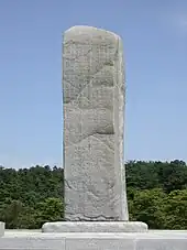 pierre taillée présentant 4 faces gravées, se dressant en pleine nature.