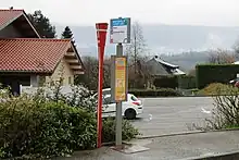 Photographie en couleurs de poteaux Lihsa et J’yBus marquant un arrêt de bus en zone urbaine à Hauteville-sur-Fier.
