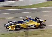 Photo d'une monoplace bleue en train de dépasser une monoplace jaune, en piste