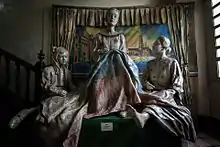 Deux femmes et une enfant assises, toutes tissant un drapeau étendu sur leur genou.