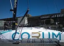 Milieu du bateau, de profil, amarré au ponton. Rouf et protection du cockpit ne sont que légèrement surélevés par rapport au pont.