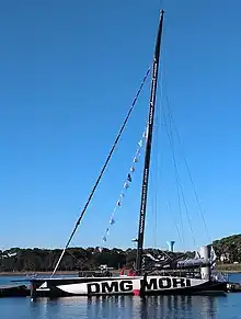 Voilier noir et blanc vu en entier, de profil, amarré à un ponton.