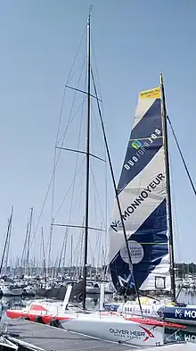 Voilier blanc et rouge vu de trois quarts avant, amarré au ponton.