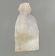 Élément en nacre gravé représentant une femme portant une flûte et un pendentif en forme de sceau-cylindre.