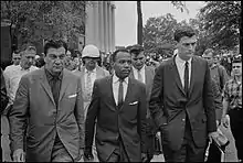 Photographie en noir et blanc de James Meredith accompagné par des hommes pour le protéger.