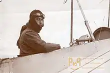 Photo montrant Jean Desparmet, en tenue d'aviateur, à bord d'un avion. Il regarde l'appareil photo.