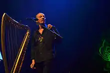 Alan Stivell sur scène au chant à côté de sa harpe celtique.