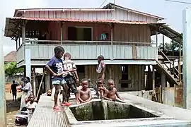 Maison sur pilotis et fontaine.