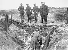 Cinq hommes en uniformes sur le parapet d'une tranchée