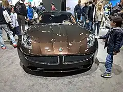 Photo de l'avant d'une voiture de luxe marron dans un stand d'exposition.