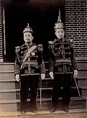Photographie de deux hommes debout faisant face au photographe. Ils portent des uniformes militaires de cérémonie.