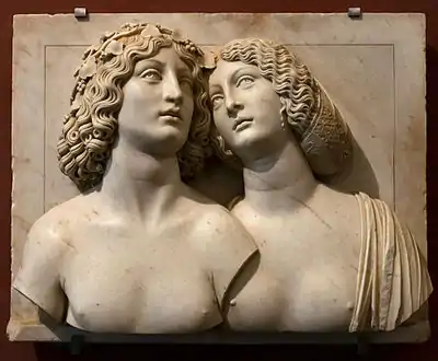 Image d'une œuvre montrant les deux bustes en relief d'un jeune couple dans le fond d'un cadre en marbre.