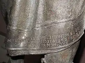  Partie d'une statue avec une inscription.