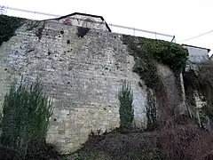 En contrebas de l'église dont on aperçoit une partie du chevet, la falaise est maintenue par un haut mur percé par un escalier raide et étroit que l'on remarque à droite.