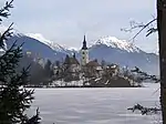 Le lac de Bled gelé en hiver. Au fond à droite, le Begunjščica.