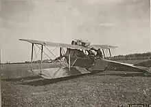 Photo noir et blanc d'un avion biplan posé au sol.