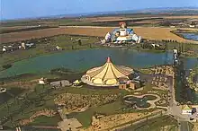 Photographie aérienne du parc, avec un chapiteau au premier plan, un grand bassin et, au fond, la statue gigantesque de Gargantua.