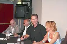 Trois hommes et une femme d'une cinquantaine d'années, menant une séance de dédicaces.