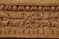 Photographie de la partie centrale du linteau de la porte du minaret. D'origine antique (morceau de soffite), il est orné d'un décor sculpté de pampres et de perles.