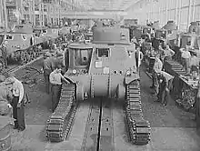 photographie en noir et blanc montrant des ouvriers en train d’installer les chenilles sur un char en construction