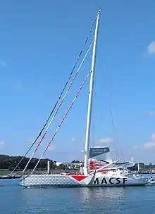 Voilier gris avançant au moteur, vu en entier, de profil.