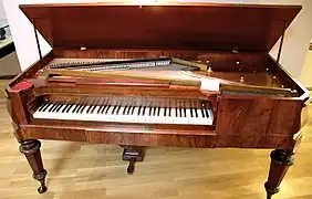 Un piano à queue carré ouvert.