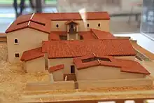 Photographie de maquette d'une maison romaine où une colonnade supporte un étage.