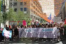 Une foule de gens derrière une bannière qui se lit « marche pour le droit des personnes trans migrantes »