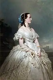 revêtue d'une ample robe à crinoline satinée de teinte claire, Marie-Henriette pose debout, de profil, les cheveux coiffés en anglaises et couverts d'une voile en dentelle retenu par un nœud bleu