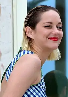  Photographie en couleurs et prise de trois-quarts dos d'une femme adressant un clin d'œil à l'objectif.