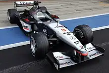 Photo d'une monoplace noire et argentée dans une voie des stands