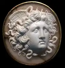 Dans un camée circulaire, tête de jeune femme de trois-quarts face avec une abondante chevelure où s'emmêlent de petits serpents. Elle a deux ailes sur les côtés de la tête.