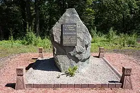 Un rocher entouré de quatre mini-chevalements en béton porte une plaque de marbre. Inscription : À la mémoire des 4 victimes de l'Étançon le 16 décembre 1950, Billequey Louis, Demesy martial, Jenroy Marius et Kortitzko Gerard.