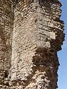 Photographie en couleurs d'un mur dont le bord est constitué de pierres de taille.