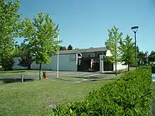 Photographie en couleurs d'un bâtiment dont un mur prote une reproduction d'une signature de Jean Cocteau.